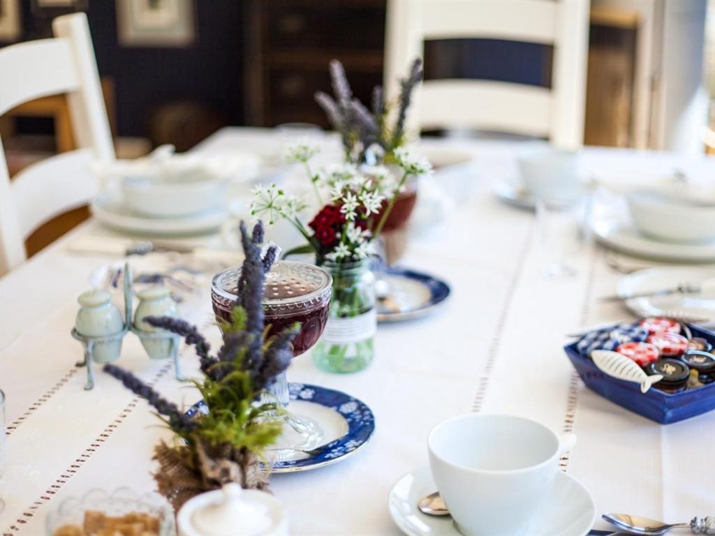 a table with plates and cups and flowers on it at Birch House Bed & Breakfast in Weymouth