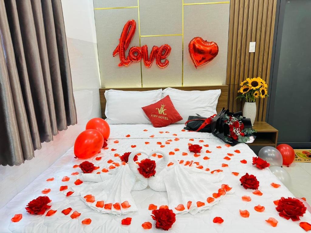 un lit avec des fleurs rouges et des ballons dessus dans l'établissement Khách Sạn K’My, à Ấp Phú Thọ