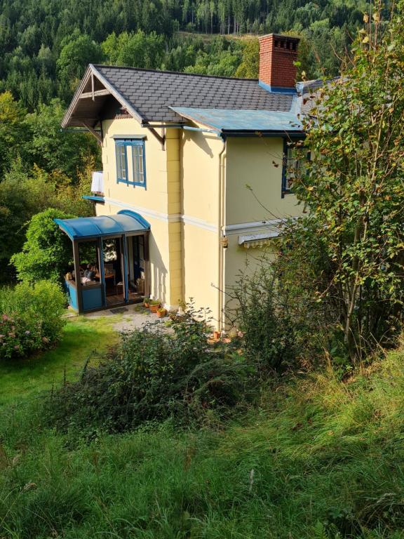 uma pequena casa amarela com um telhado azul em Villa Anima em Prein