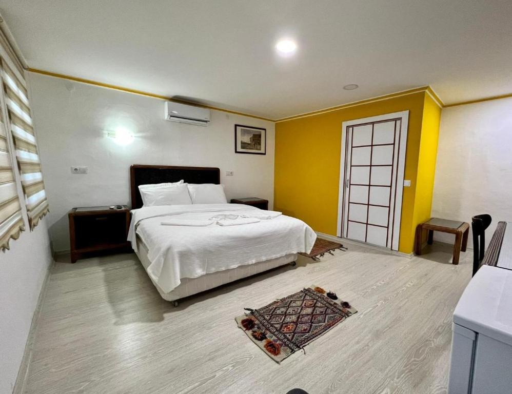a bedroom with a white bed and yellow walls at TAG Pansiyon in Antalya