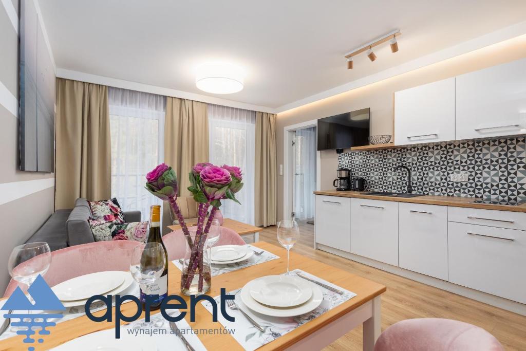 a kitchen and living room with a table and chairs at Apartament AURI Pobierowo Baltic Apartments - Aprent in Pobierowo