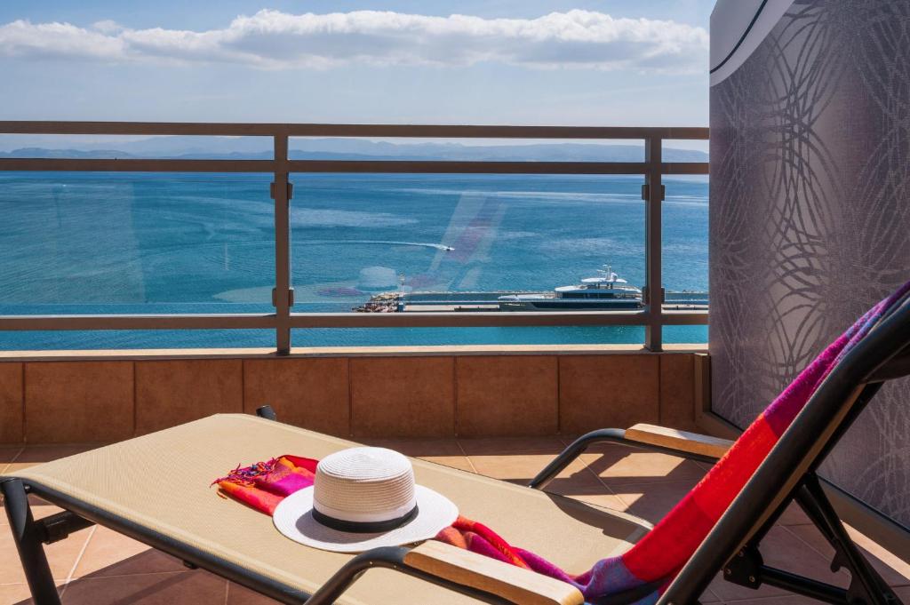 a hat sitting on a chair on a balcony with a cruise ship at Minos Boutique Hotel in Agia Galini