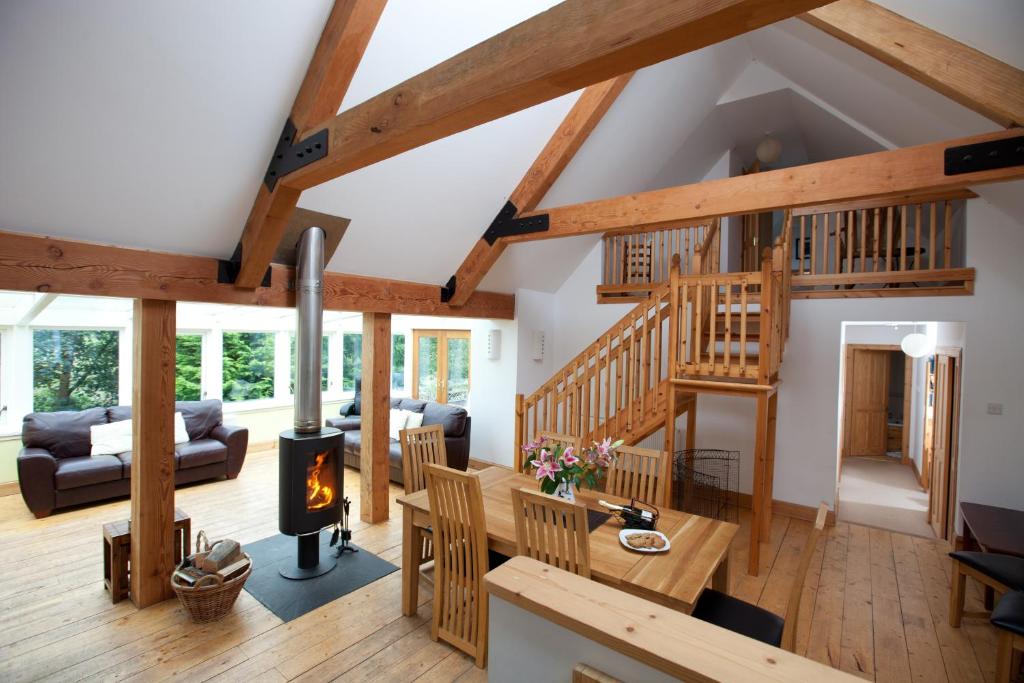 una sala de estar abierta con chimenea y vigas de madera. en The Byre, Back Borland Holday Cottages en Stirling