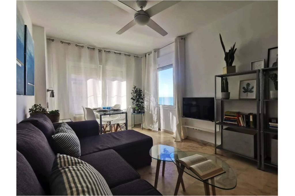 Una sala de estar con un sofá y un ventilador de techo. en Romántica vista al paseo marítimo de Cádiz, en Cádiz