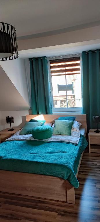 Un dormitorio con una cama con almohadas azules y una ventana en Pokoje u Marioli en Łeba