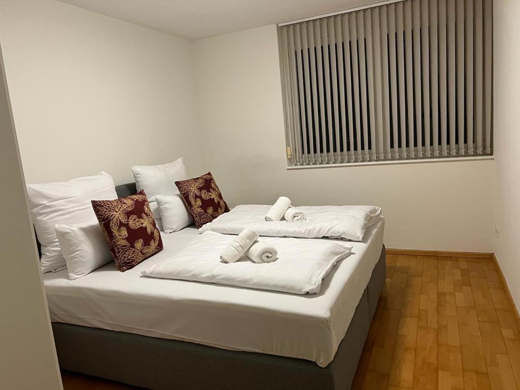 łóżko z białą pościelą i poduszkami w pokoju w obiekcie Cocoon am Schloß w mieście Lochau