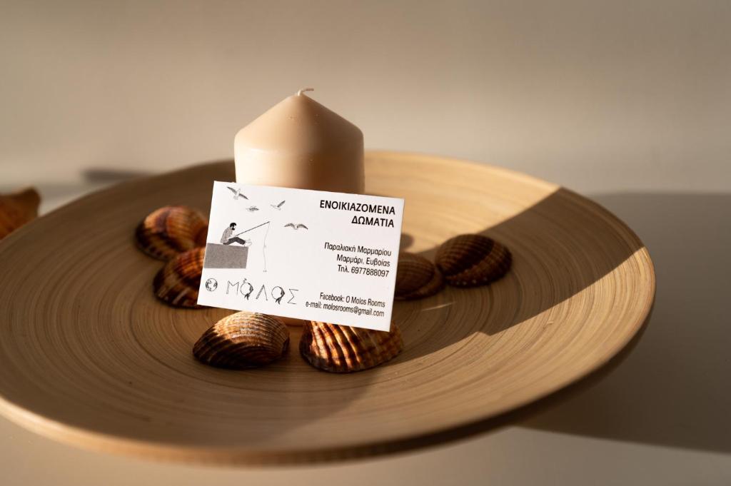a candle sitting on top of a wooden plate with nuts at Ο Μόλος in Marmarion