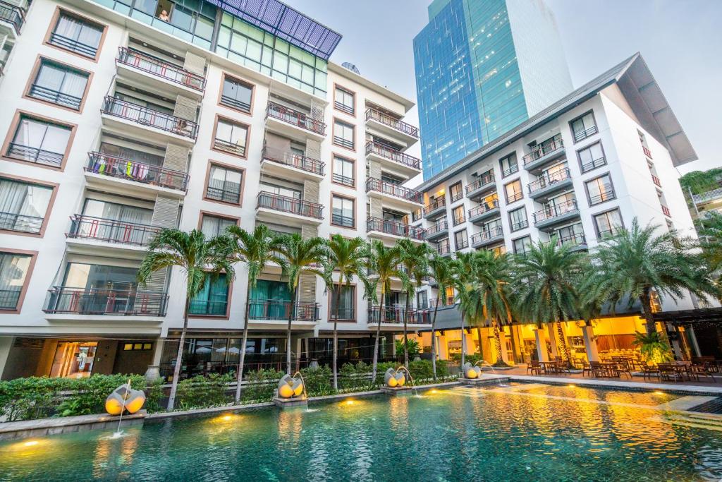 A palm-lined courtyard pool framed by hotel buildings and a high-rise tower.