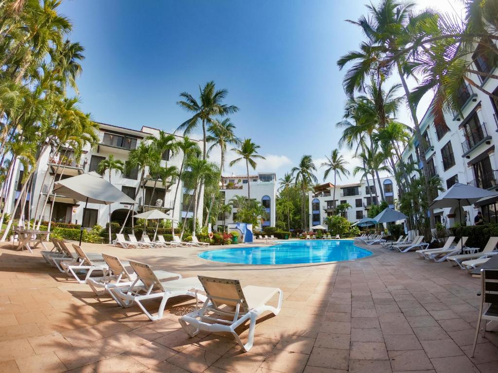 un complexe avec des chaises, une piscine et des palmiers dans l'établissement Puerto de Luna Pet Friendly and Family Suites, à Puerto Vallarta