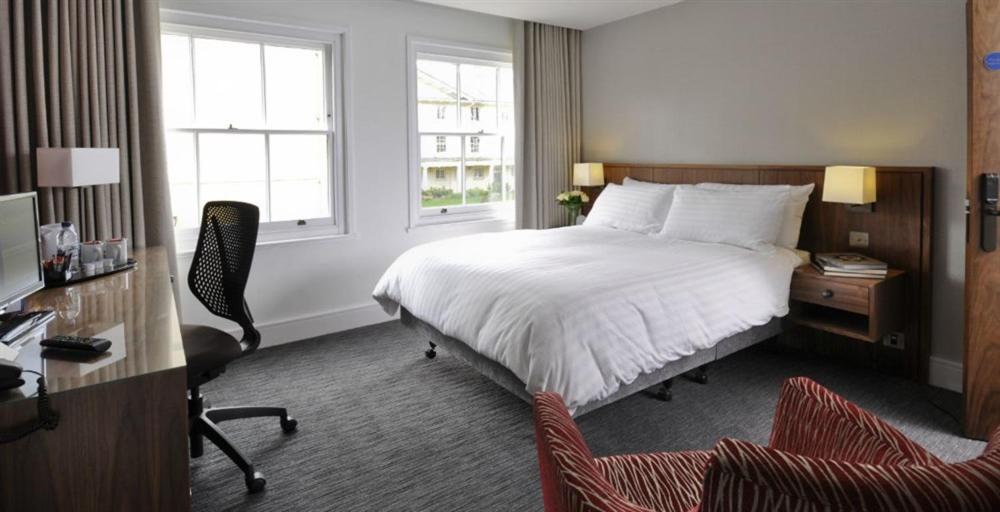 a hotel room with a bed and a desk and chairs at Downing College in Cambridge