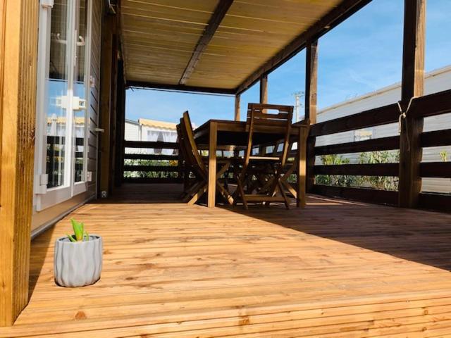 une terrasse couverte en bois avec une table et une chaise. dans l'établissement Mobil home 6/8 personnes camping 4*Frejus, à Fréjus