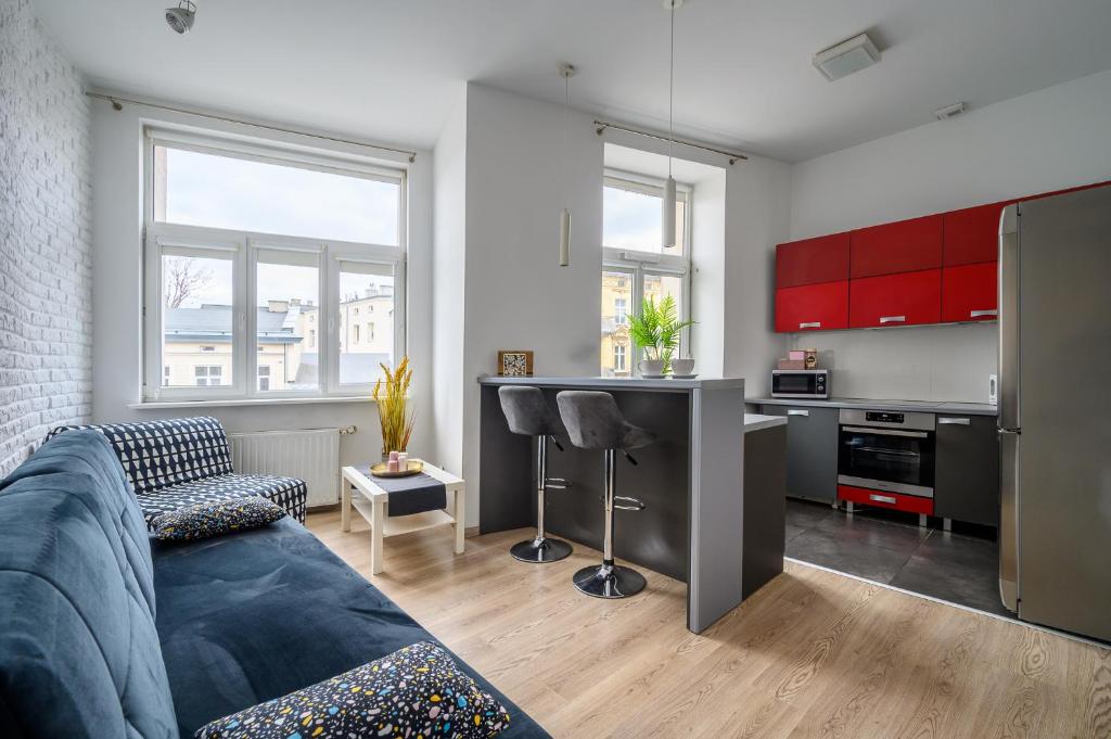 a living room with a couch and a kitchen with red cabinets at Rent-Apart City Center Kopernika in Łódź