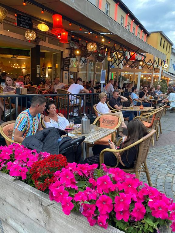 un groupe de personnes assises dans un restaurant en plein air avec des fleurs dans l'établissement Hotel Montagna Delmondo, à Fauquemont