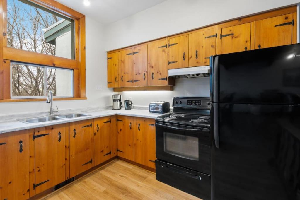 a kitchen with a black refrigerator and wooden cabinets at 3 Level Ski Chalet 7BR w Deck, Sauna & Ping-Pong! in Blue Mountains