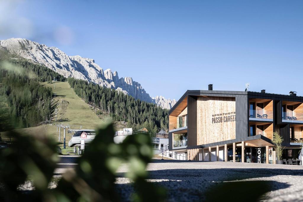a large building with a mountain in the background at Sport Hotel Passo Carezza in Vigo di Fassa