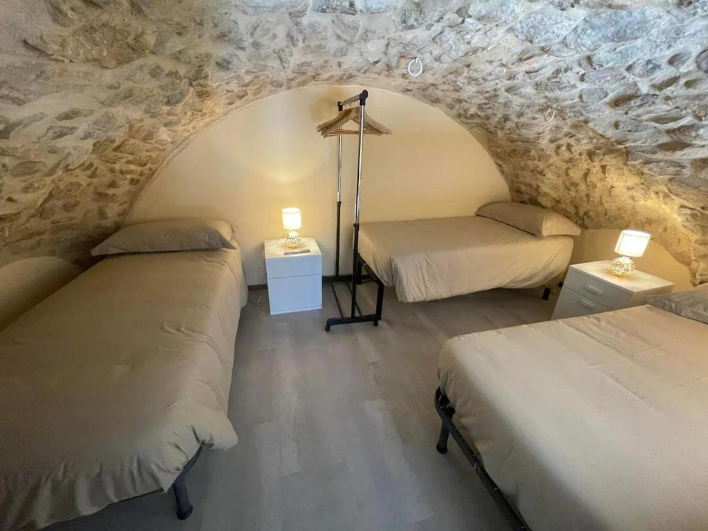 2 camas en una habitación con una pared de piedra en Puteha - Arco Pronti, en SantʼAgata di Puglia