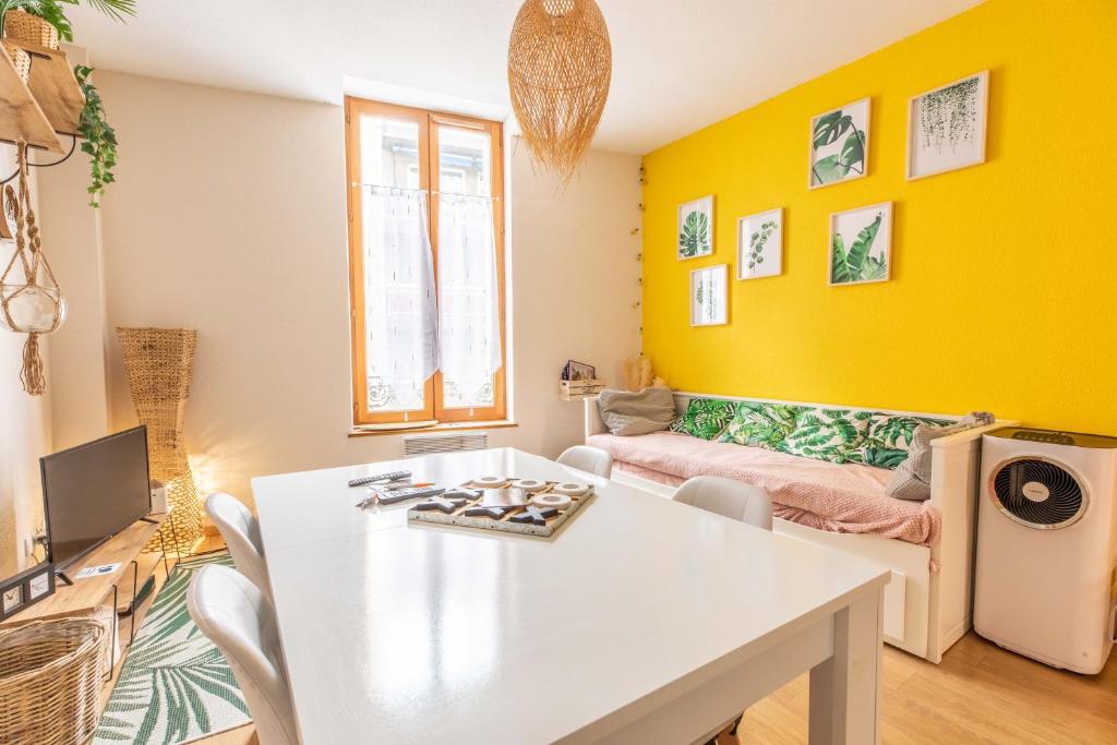 ein Wohnzimmer mit einem weißen Tisch und gelben Wänden in der Unterkunft Evasion Centre-ville 2 à 8 personnes in Clermont-Ferrand