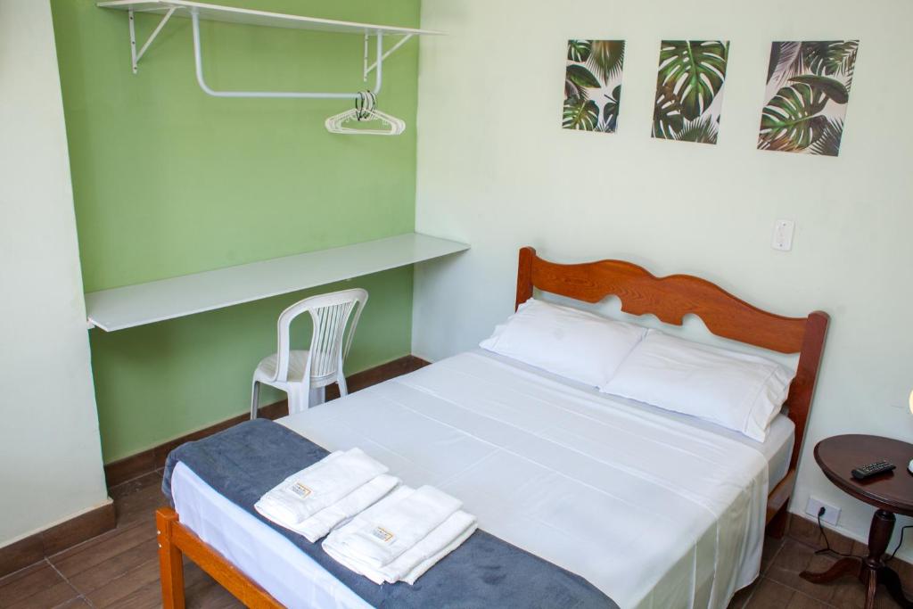 a bedroom with a bed and a table with a chair at Pousada Chácara Maria da Graça in Tremembé