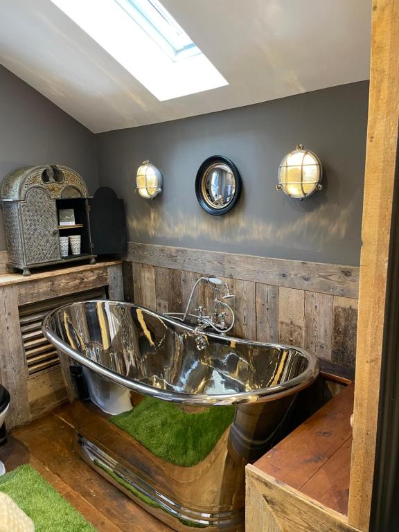 La salle de bains est pourvue d'une baignoire et de murs en bois. dans l'établissement The Cocktail Lounge at Cheshire Boutique Bathhouse, à Nantwich