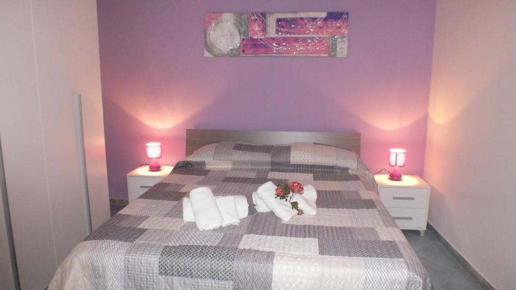 カステッランマーレ・デル・ゴルフォにあるSicania holiday house 1の紫の壁のベッド1台、ランプ2つが備わるベッドルーム1室が備わります。