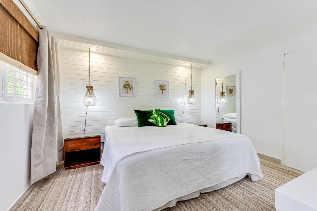a white bedroom with a large white bed with a green pillow at The Palms Resort in Saint James