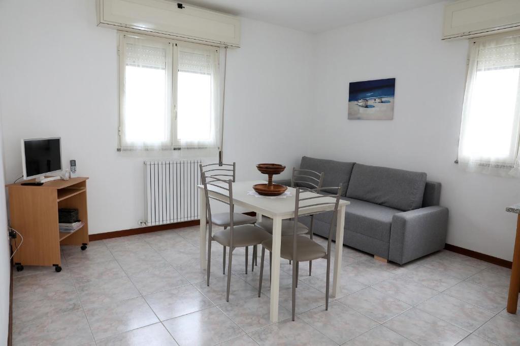 un soggiorno con tavolo, sedie e divano di Appartamento da Luca a Calasetta