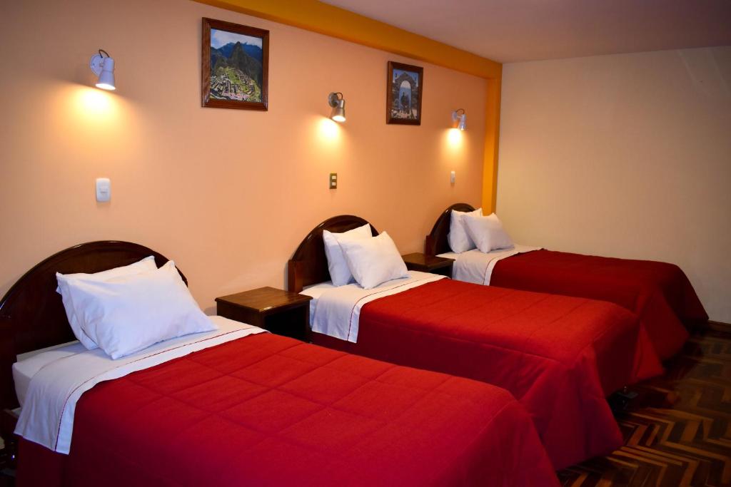 Habitación de hotel con 2 camas con sábanas rojas en Hostel Sol Andina Inn, en Puno