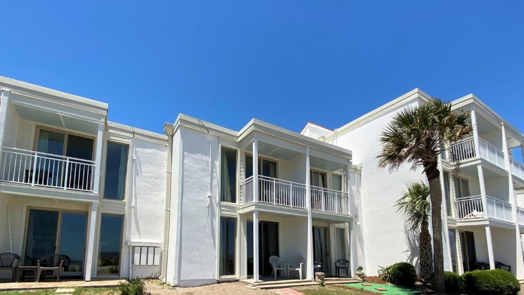 a white building with a palm tree in front of it at Villas by The Sea Deluxe Two Bedroom Apartment in Jekyll Island
