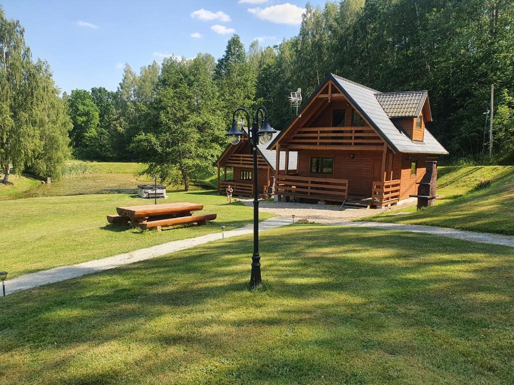 a log cabin in a field with a light pole at Mana Village - Jacuzzi & Sauna in Barłomino