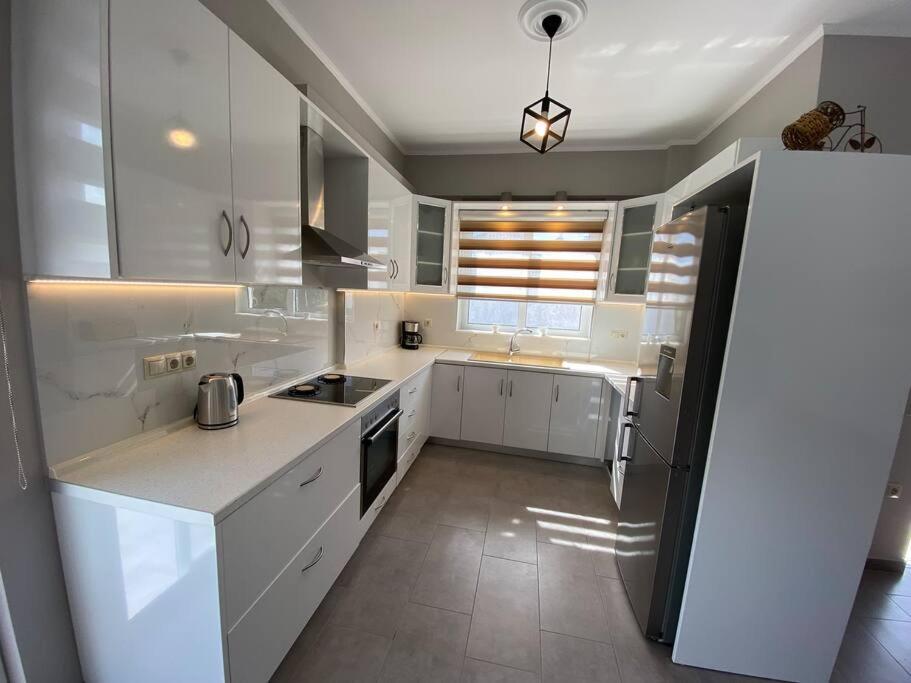 eine Küche mit weißen Schränken und einem weißen Kühlschrank in der Unterkunft Keskos Luxury Villa in Artemida