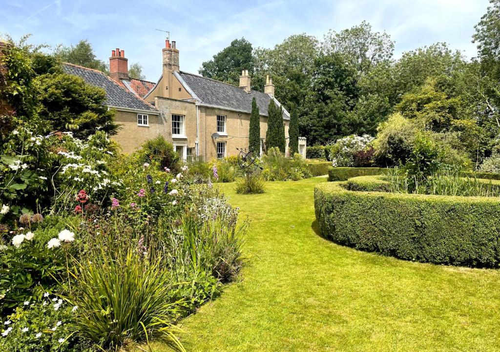 a garden in front of a house with bushes at Dilham House in Dilham