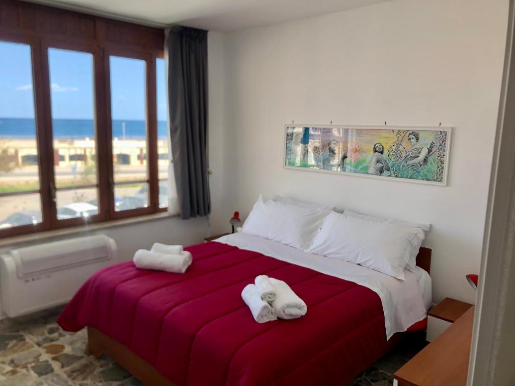 een slaapkamer met 2 handdoeken op een bed met een raam bij Delos e Artemide in Siracusa