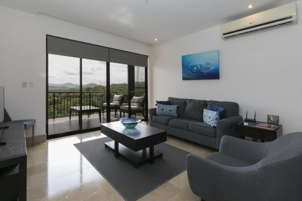 a living room with a couch and a table at Roble Sabana 304 Luxury Apartment - Reserva Conchal in Playa Conchal
