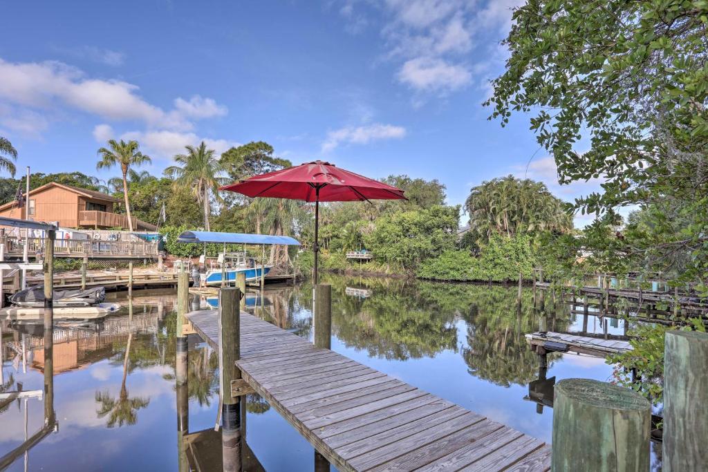 a wooden dock with an umbrella on a body of water at Stuart Vacation Rental Walk to Private Boat Dock! in Stuart