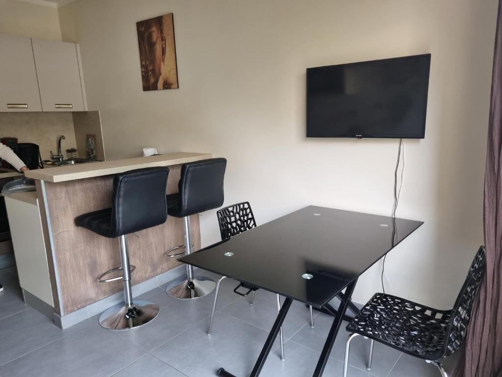 uma mesa preta com cadeiras e uma televisão na parede em Studio climatisée dans résidence à 5 minutes des plages a pied em Propriano