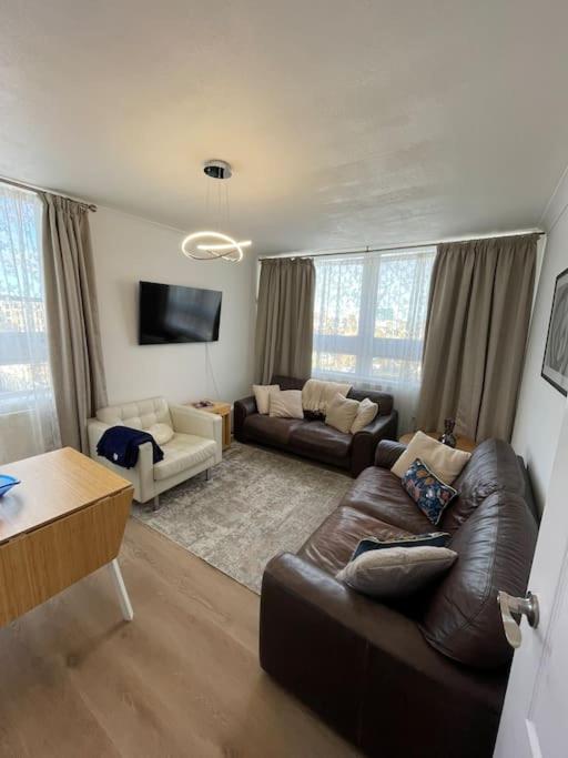 a living room with a leather couch and a tv at Great Location 4 bedroom in London