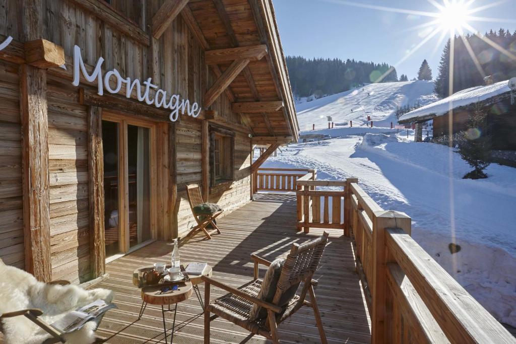 een houten terras met stoelen en een skihut bij Le Lodge Chasse Montagne in Les Gets