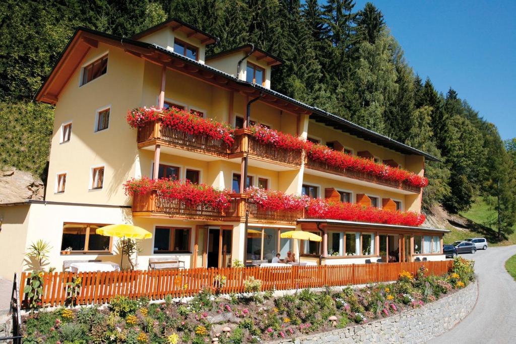 un bâtiment avec des fleurs et des parasols devant lui dans l'établissement Hotel Raunig, à Bad Kleinkirchheim