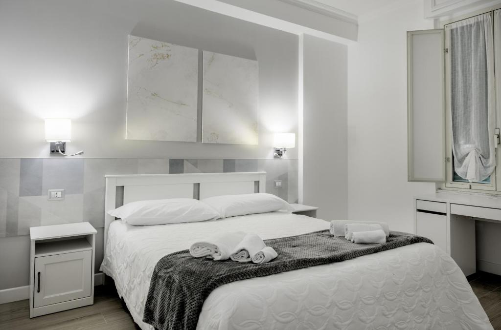 a bedroom with a large white bed with towels on it at Guest House Romano in Rome