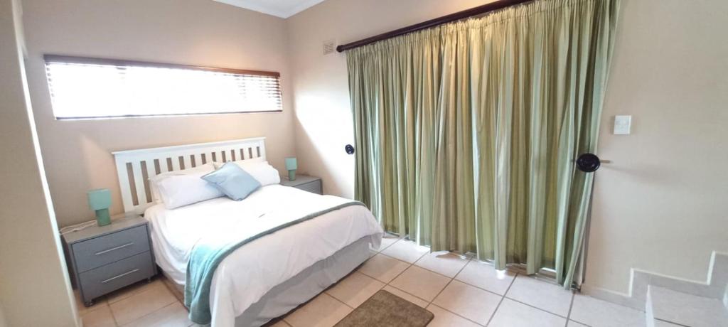 a bedroom with a bed and a large window at SUNSET REST BEACH VILLA in Margate