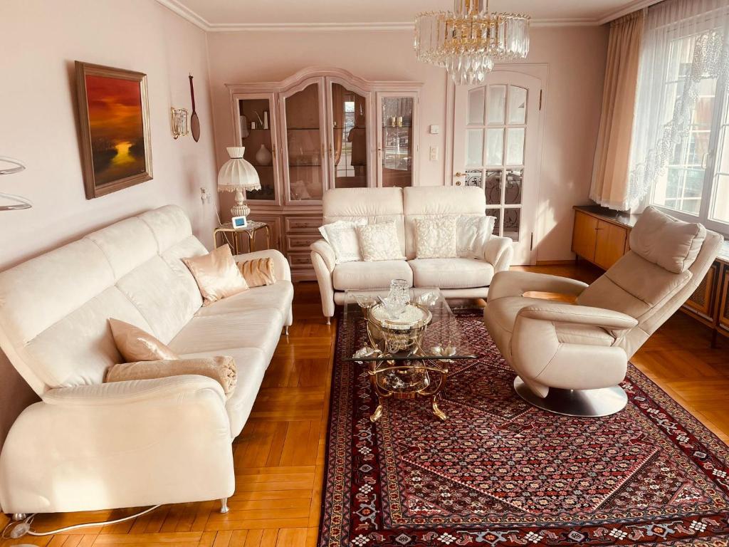 ein Wohnzimmer mit weißen Möbeln und einem Kronleuchter in der Unterkunft Haus Bohle in Dornbirn