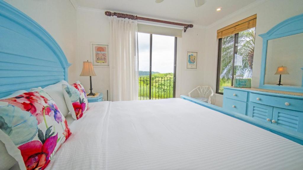 Un dormitorio con una cama grande y una ventana en Bougainvillea 3103 Luxury Apartment - Reserva Conchal, en Brasilito