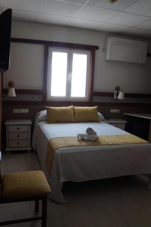 a bedroom with two beds and a television in it at Hostal La Conileña in Conil de la Frontera