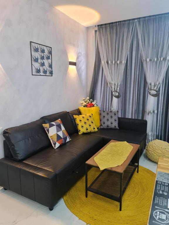 sala de estar con sofá de cuero negro y almohadas amarillas en Reem Suite, en Nahariyya