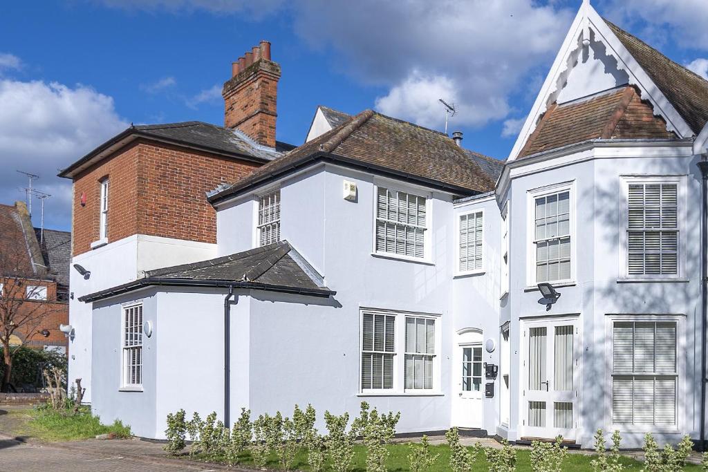 uma casa branca com uma chaminé e um edifício de tijolos em Ipswich Town Centre - Apartment 1 em Ipswich