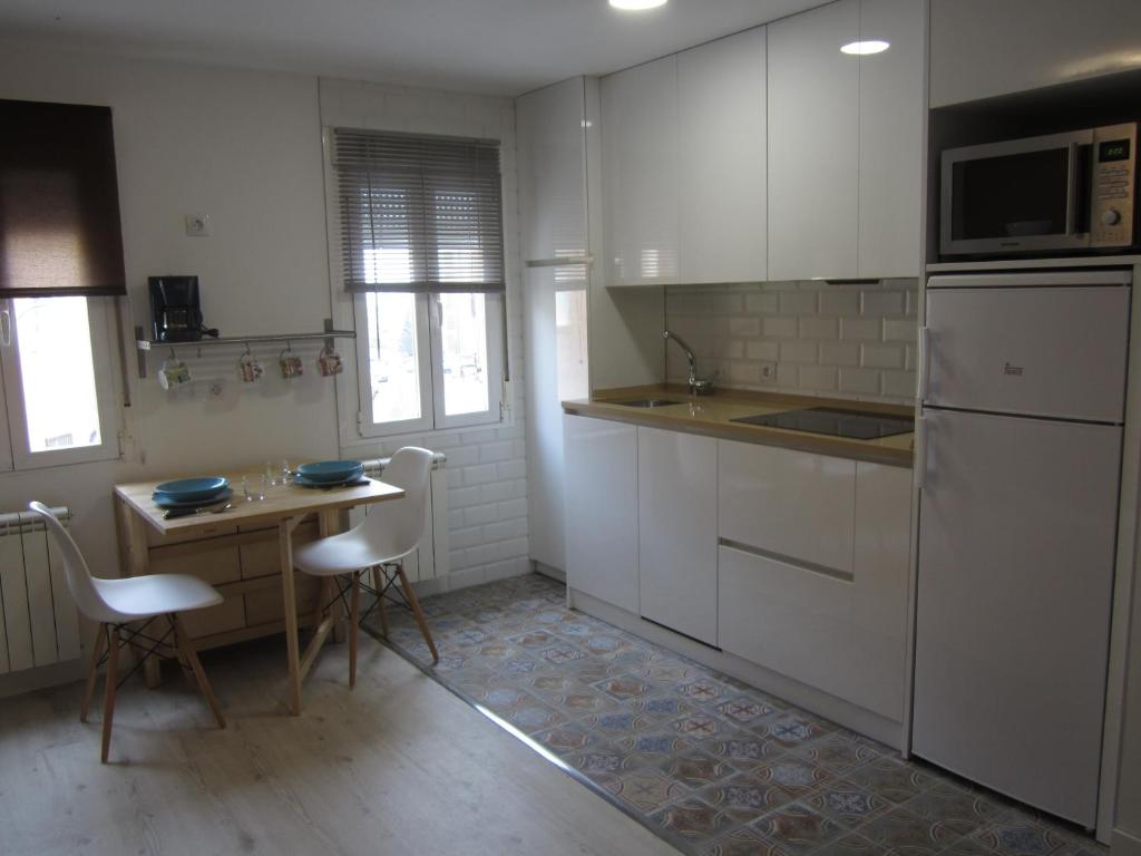 ブルゴスにあるLoló Vivienda de uso Turístico 09-27の白いキャビネット、テーブルと椅子付きのキッチンが備わります。