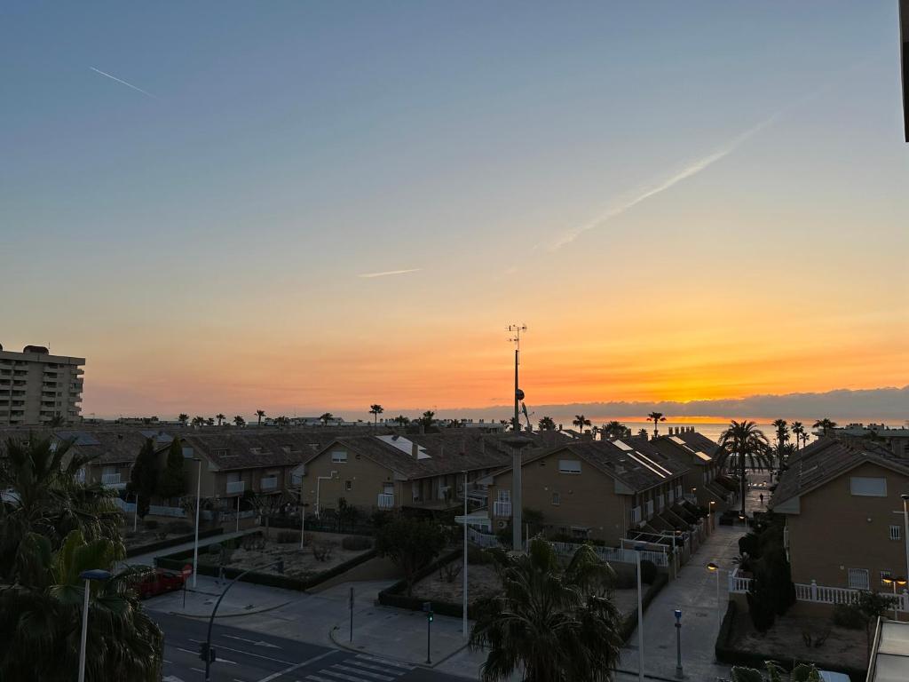 einen Sonnenuntergang über einer Stadt mit Häusern und Palmen in der Unterkunft Sunny Patacona Seaview in Valencia