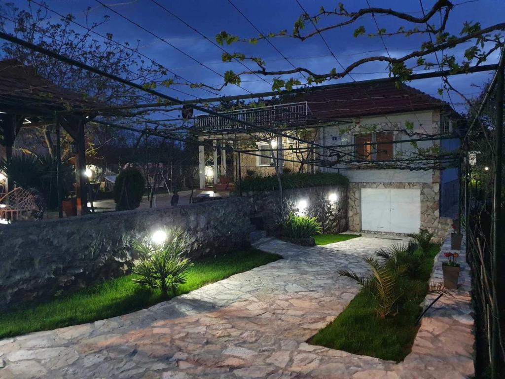 ein Haus mit einer Steinmauer und einer Steinzufahrt in der Unterkunft Green House Pejovic in Podgorica