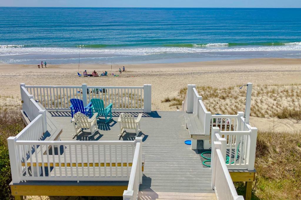 a wooden boardwalk leading to a beach with chairs and the ocean at Colony by the Sea #201 in Indian Beach