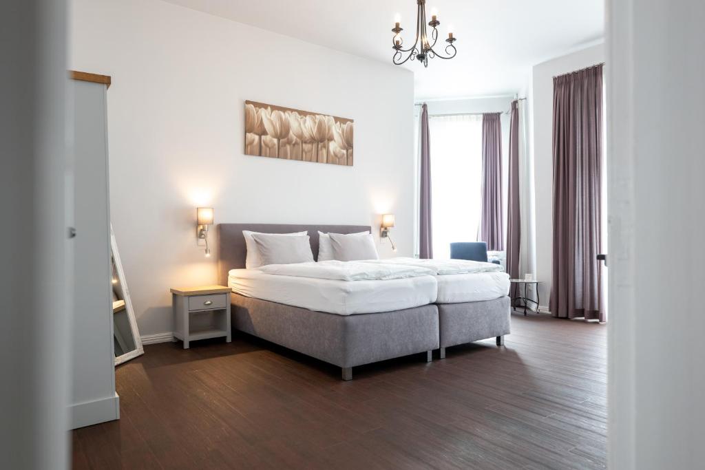 ein weißes Schlafzimmer mit einem Bett und einem Kronleuchter in der Unterkunft Maritas Logierhaus (Haus Braunschweig) in Westerland